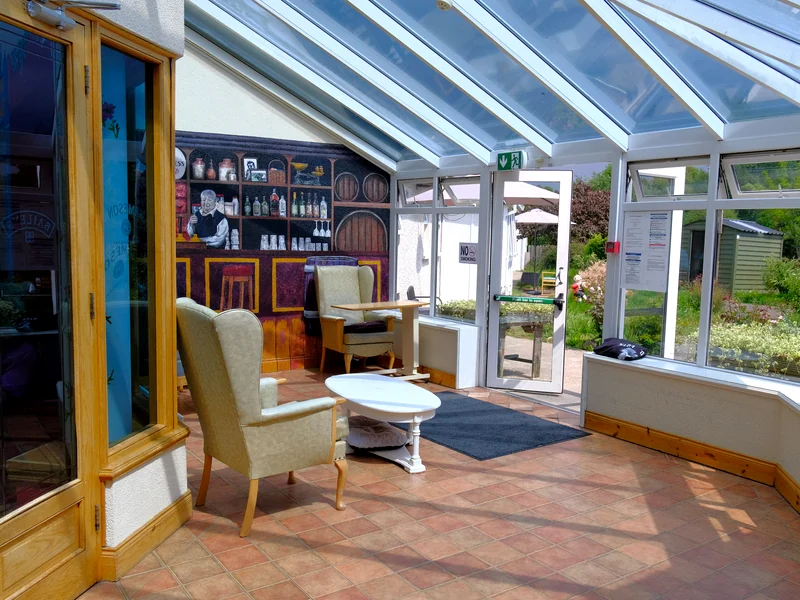 Sun room seating beside the garden at Rivervale Nursing Home